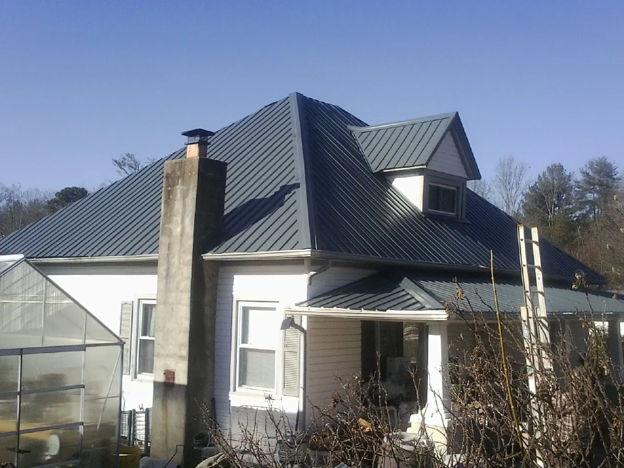 Dark blue standing seam metal roof on a white farmhouse with dormer — Slate & Tile Roof Repair by Roofing Brothers in Duffield
