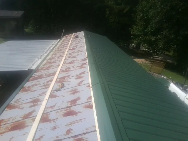 Old rusted panels beside newly installed green metal roofing — Wind Damage Roof Repair by Roofing Brothers in Duffield