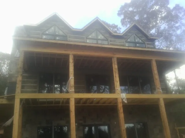 Dormers and porch framing on a large log home under construction — Roof Coating work by our crew in Duffield