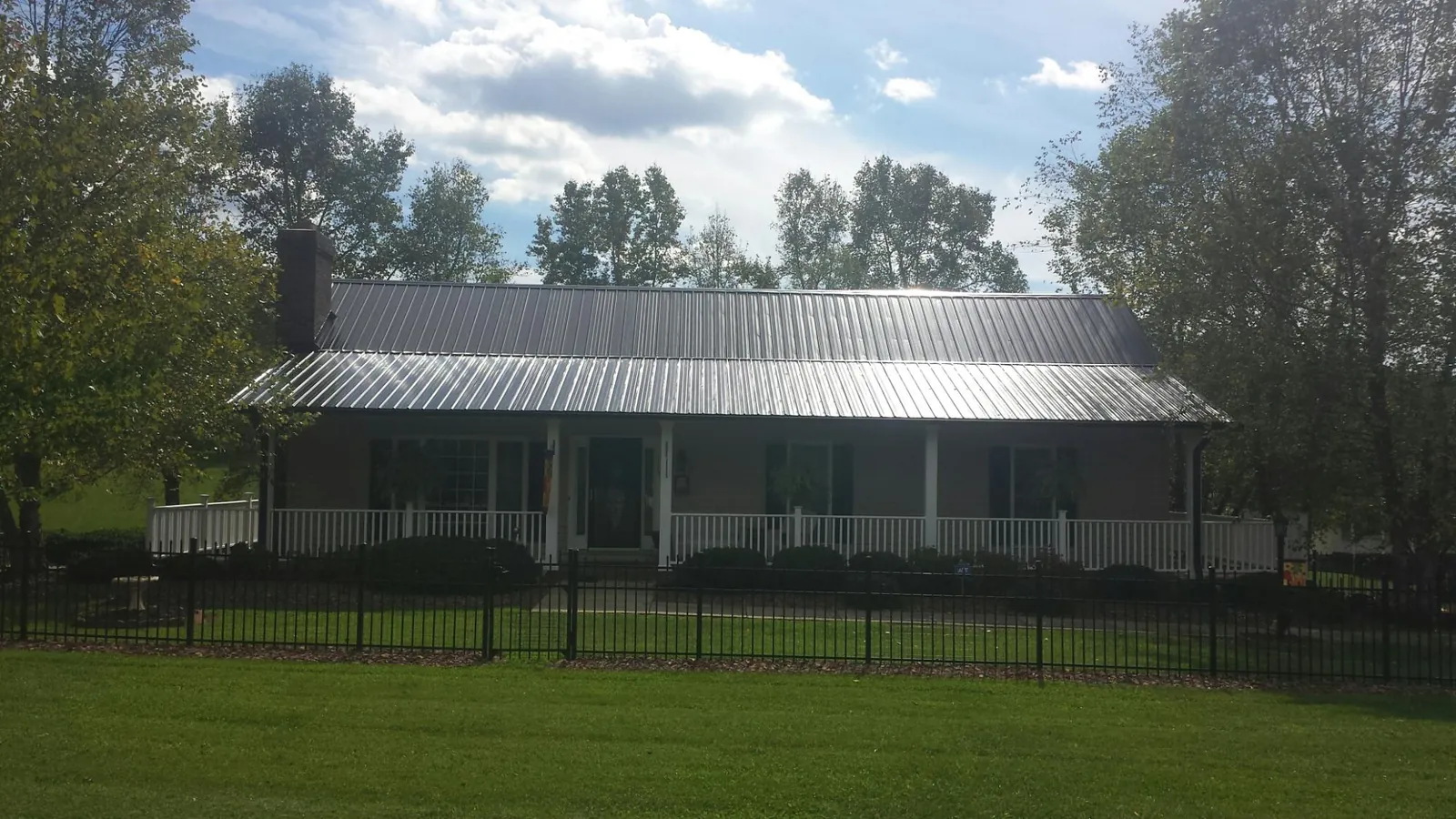 Gray metal roof on a brick ranch with a full width front porch — Gutter Guard Installation work by our crew in Duffield